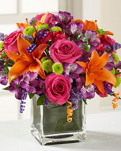 Birthday blooms that are ready to get your recipient's special day started, this flower bouquet is bright, happy, and ready to celebrate! Hot pink roses and orange Asiatic Lilies are vibrant and fun surrounded by purple Peruvian Lilies, hot pink mini carnations, green button poms, purple statice, and an assortment of lush greens. Accented with assorted curling ribbons to give it that party feels and presented in a clear glass cubed vase lined with ti leaf green material for added beauty, this unforgettable birthday bouquet is that ultimate surprise that will make them feel the love on their big day.

STANDARD bouquet includes 11 stems.
Approximately 10H x 10W.
C Quantity Color Description
2 Hot Pink 50 cm Standard Rose
1 Orange Asiatic Lily
3 Purple Alstroemeria
2 Green Button Pom
2 Hot Pink Miniature Carnation
1 Purple Filler - Sinuata Statice
2 Green Green - Leather Leaf
1 Green Green - Pittosporum
0.33 Green Green Flexible Leaf Material
1.5 Curling Ribbon (yds.)
0.33 Green Florist Foam Brick

DELUXE bouquet includes 15 stems.
Approximately 11H x 11W.
C Quantity Color Description
4 Hot Pink 50 cm Standard Rose
1 Orange Asiatic Lily
3 Purple Alstroemeria
2 Green Button Pom
3 Hot Pink Miniature Carnation
2 Purple Filler - Sinuata Statice
2 Green Green - Leather Leaf
1 Green Green - Pittosporum
0.33 Green Green Flexible Leaf Material
1.5 Curling Ribbon (yds.)
0.33 Green Florist Foam Brick

PREMIUM bouquet includes 19 stems.
Approximately 12H x 12W.
C Quantity Color Description
5 Hot Pink 50 cm Standard Rose
2 Orange Asiatic Lily
4 Purple Alstroemeria
3 Green Button Pom
3 Hot Pink Miniature Carnation
2 Purple Filler - Sinuata Statice
2 Green Green - Leather Leaf
1 Green Green - Pittosporum
0.66 Green Green Flexible Leaf Material
3 Curling Ribbon (yds.)
0.5 Green Florist Foam Brick