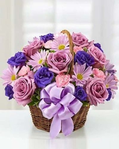 <p>Hand-designed in a charming handled basket and accented with a satin ribbon, this Basket of Blossoms is sure to make her smile. This beautiful arrangement is filled with roses, lisianthus and daisies in rich shades of purple and lavender.</p>