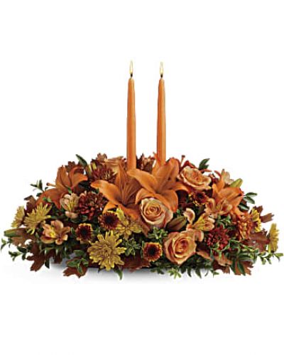 Graciously gather your family around the warm glow and classic autumn colors of this stunning Thanksgiving centerpiece. A lush variety of burnt orange blooms are gathered under a pair of tall, graceful candles - perfect for decorating your Thanksgiving dinner table, entryway or hearth.