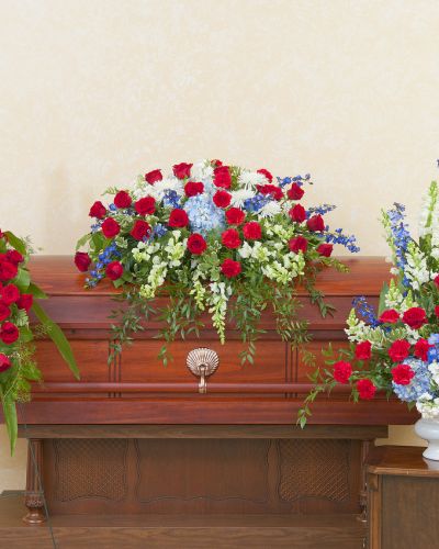 A patriotic casket spray, standing spray, and urn in red, white and blue.